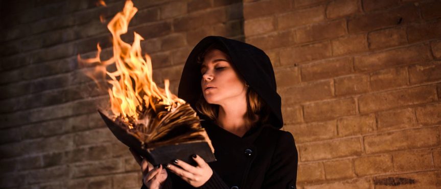 Young woman with burning book in hands (Shutterstock/Mikhail Klyoshev)